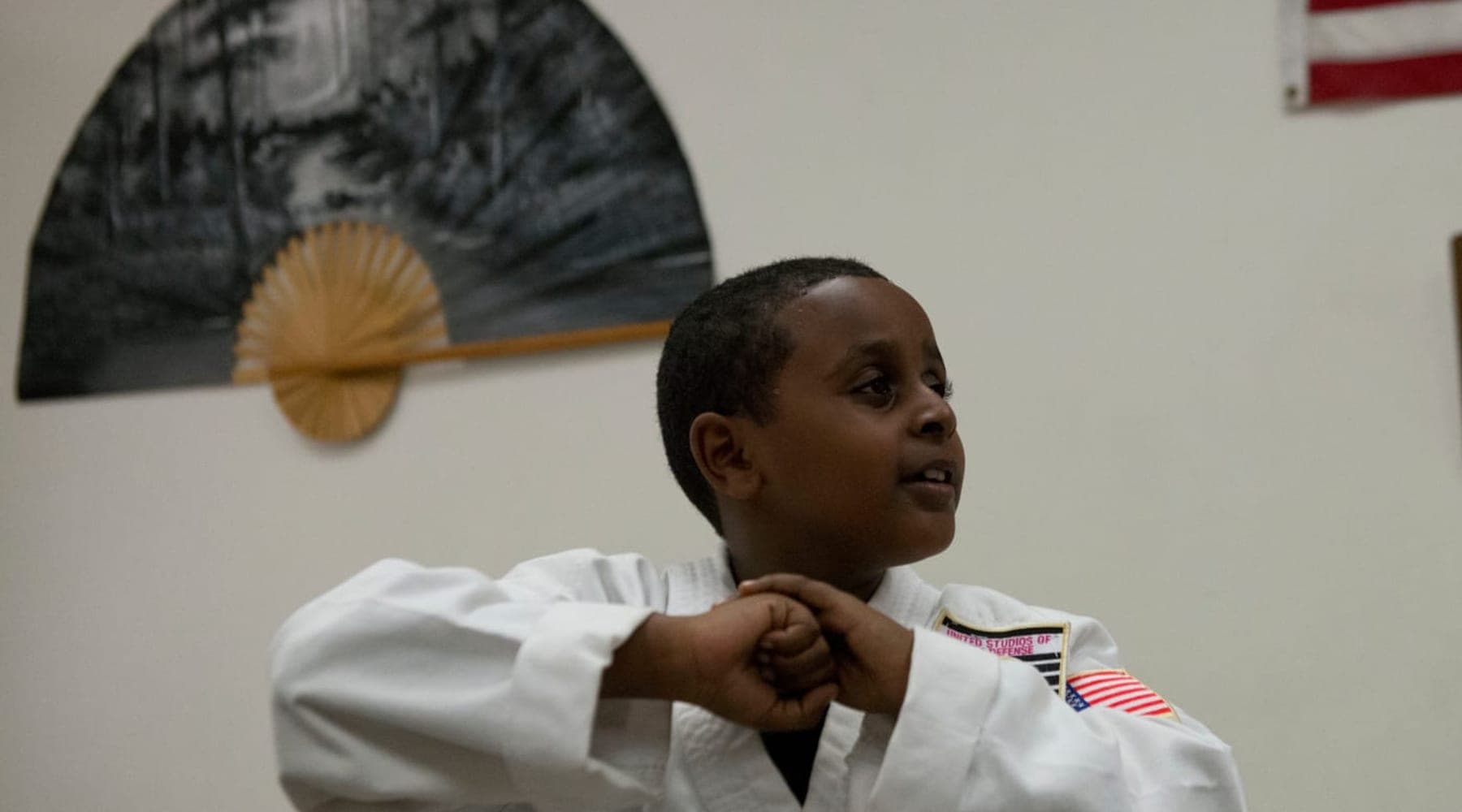 A young karate student in a white gi holding a guard stance during class at USSD Santa Barbara.