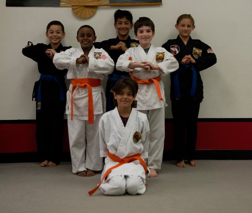 Six young karate students in white and black gis standing together in a salute at USSD Santa Barbara.