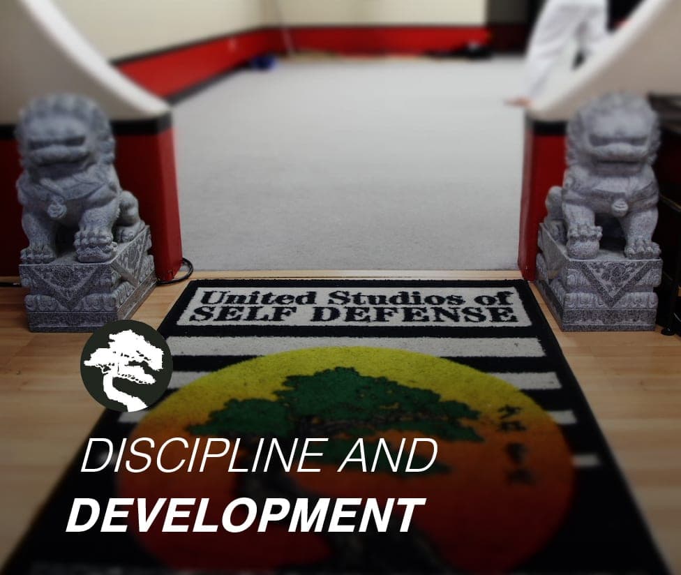 The entrance to the USSD Santa Barbara training floor, flanked by stone guardian lions, with a United Studios of Self Defense mat, captioned 'Discipline and development.'