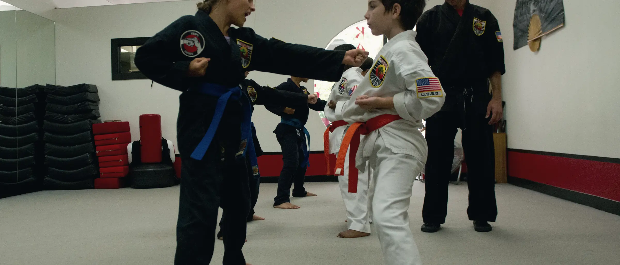 An instructor coaching a young student's guard through a mitt drill as other students train behind them at USSD Santa Barbara.